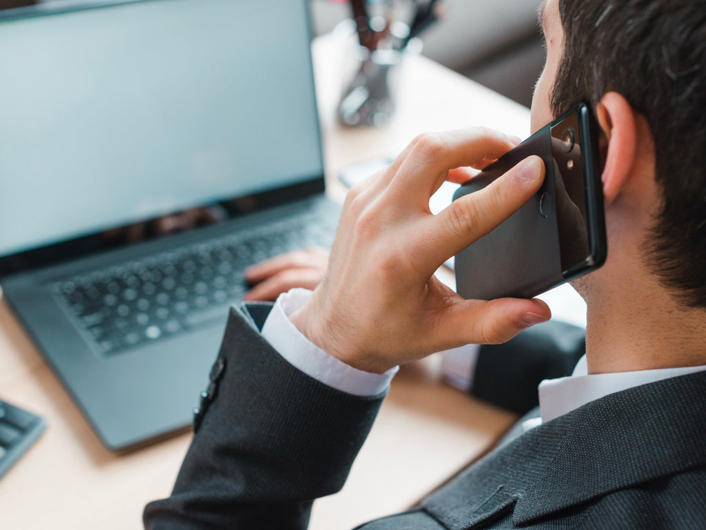 Man in a suit talking on a phone with a laptop and keyboard in the background